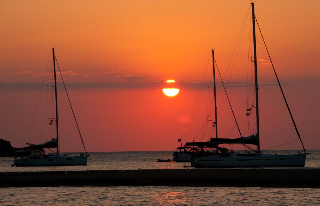 anchored sailing yachts at sunset